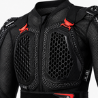 Close-up of a black protective racing jacket with honeycomb mesh panels and bright red adjustment straps on a light gray background.