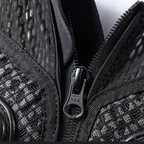 Close-up of a black textured mesh and woven bag with a black metal zipper and a visible YKK logo on the zipper pull.