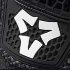 A close-up of a black honeycomb-patterned protective panel with a textured dark fabric visible along the lower left edge.