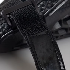 Close-up of a black woven strap with a matte black plastic buckle, shown against a dark textured background.