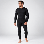 A man modeling a black long-sleeve crewneck compression shirt and matching black full-length compression pants against a light gray studio background.