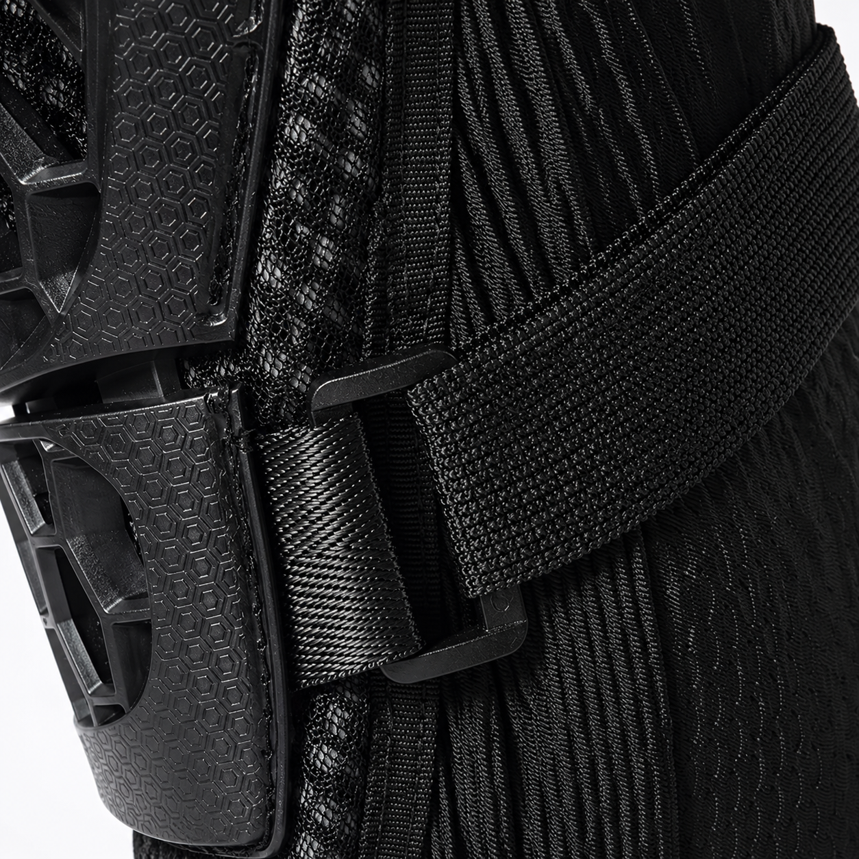 Close-up of a black protective gear item with a textured ribbed fabric body, a wide black strap, and a black plastic buckle.