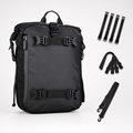 A black backpack shown on a light gray studio background with several black strap accessories arranged to the right. The backpack has multiple buckle straps and a top handle, and the accessories appear included with the product.