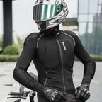 A person wearing a black full-face motorcycle helmet with a reflective visor, a black long-sleeve riding jersey with white piping and visible impact protection panels, black gloves, and a motorcycle in an outdoor urban setting.
