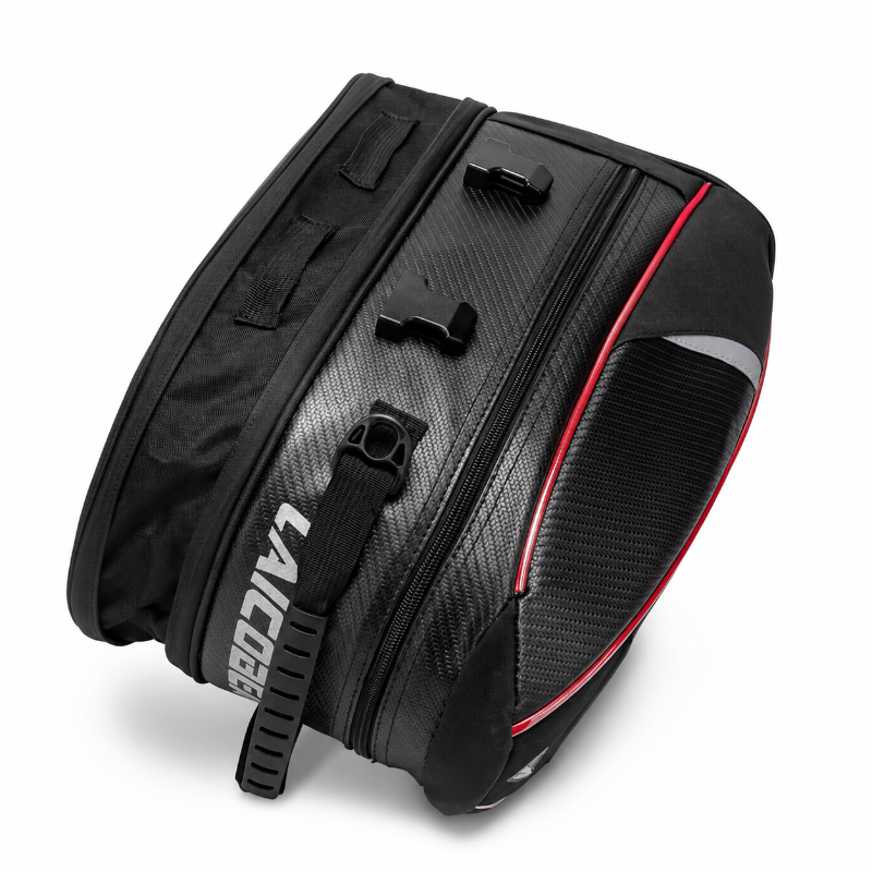 A black bicycle pannier bag with a carbon fiber textured pattern, featuring a red accent stripe, a black shoulder strap  in white, and a black reflective panel on the side.
