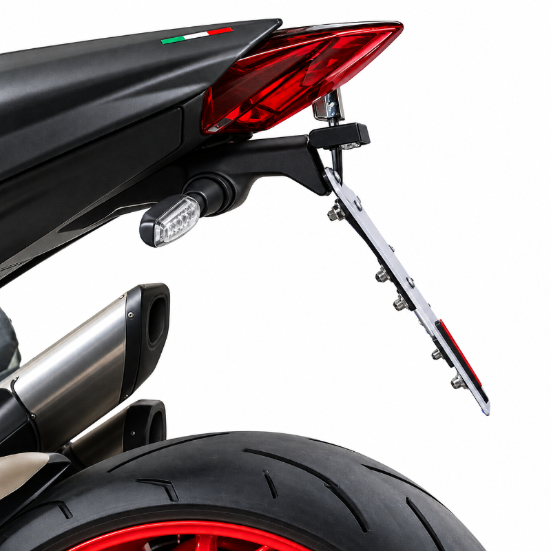 A close-up of a motorcycle rear section showing a black tail light, red reflector, side marker, exhaust pipe, and a silver license plate frame with a red and white reflector, photographed on a white background.
