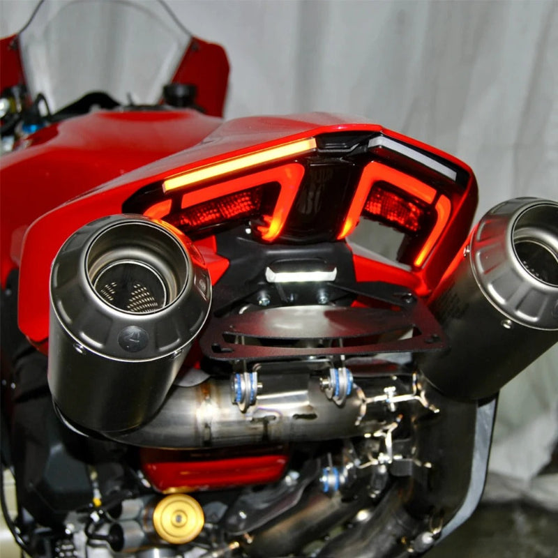 Close-up of a red motorcycle rear section showing the exhaust system with two large metallic mufflers and a black rear light assembly.