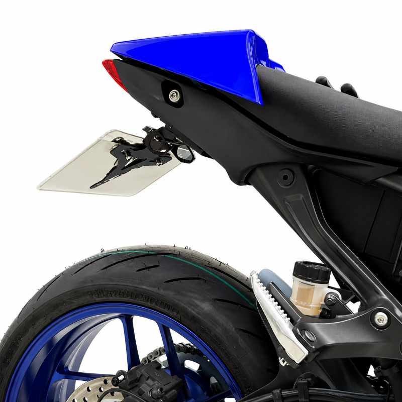Close-up of a motorcycle rear section with a clear tinted rear window, blue body panel, black seat, and blue wheel on a white background.
