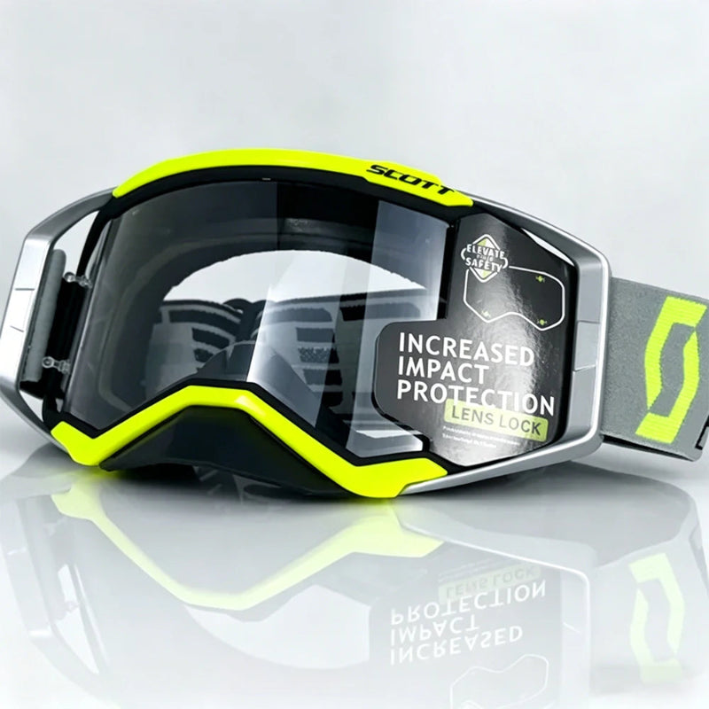 motocross goggles with a black and neon yellow frame, a clear impact-resistant lens, and a gray strap with a neon yellow logo, shown on a reflective light gray background.