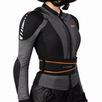A close-up side view of a person wearing a black and dark gray riding jacket with a wide black waist belt featuring orange trim and the X-ARMOR logo, against a plain white background.