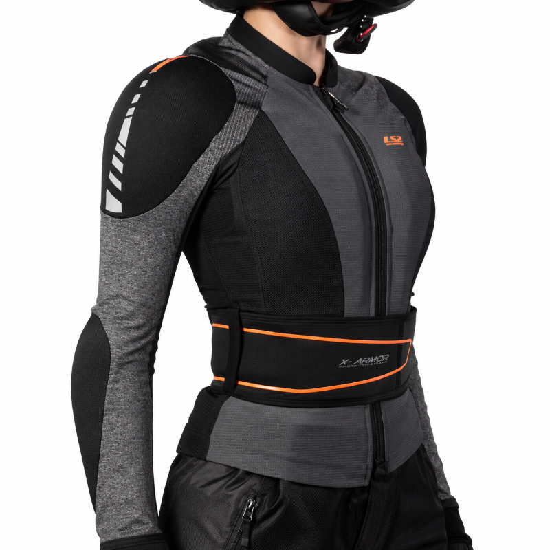 A close-up side view of a person wearing a black and dark gray riding jacket with a wide black waist belt featuring orange trim and the X-ARMOR logo, against a plain white background.