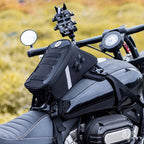 Motorcycle with a black saddlebag and handlebar camera attachment against a blurred natural background