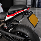 Close-up rear view of a motorcycle with a black seat, black body panels, red and white graphic stripes, a yellow license plate, and a black frame in an indoor setting.